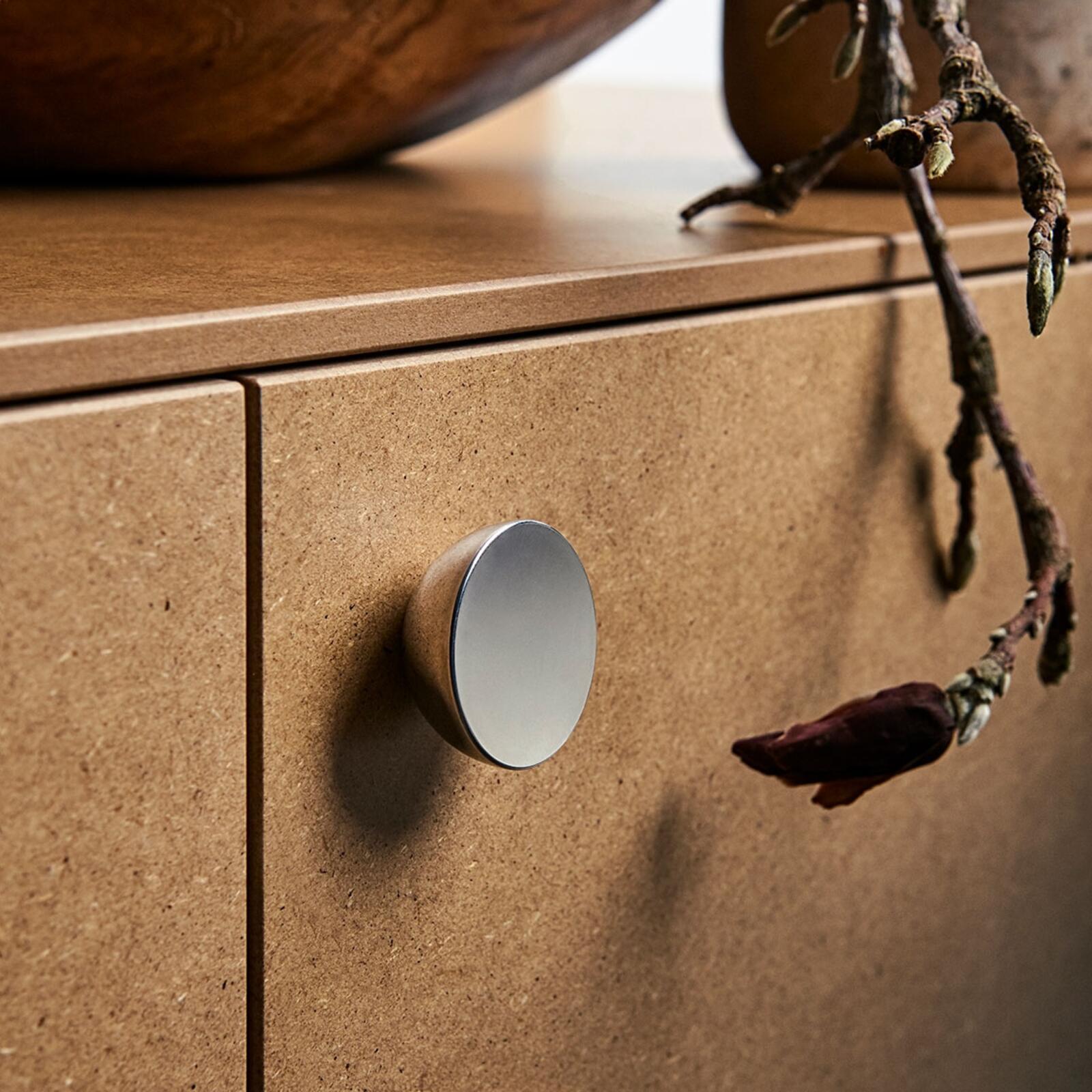 Hemisphere shaped knob in shiny metal, on cabinet fronts in clear-coated mdf