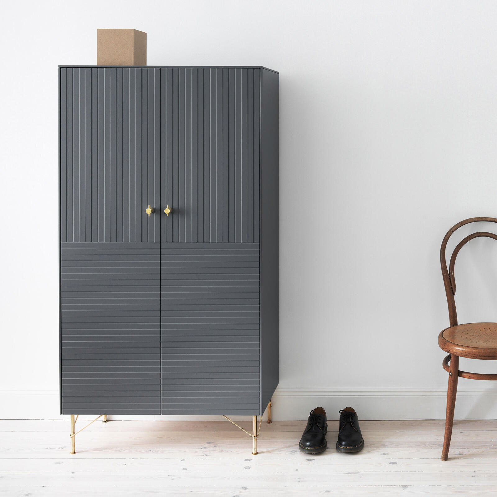 Grey cabinet with a pattern formed by vertical and horizontal lines, knobs and furniture legs in solid brass